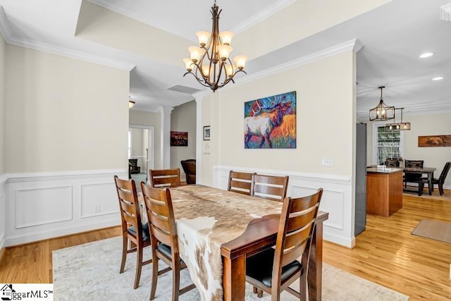 dining room with light wood-style floors, an inviting chandelier, and crown molding