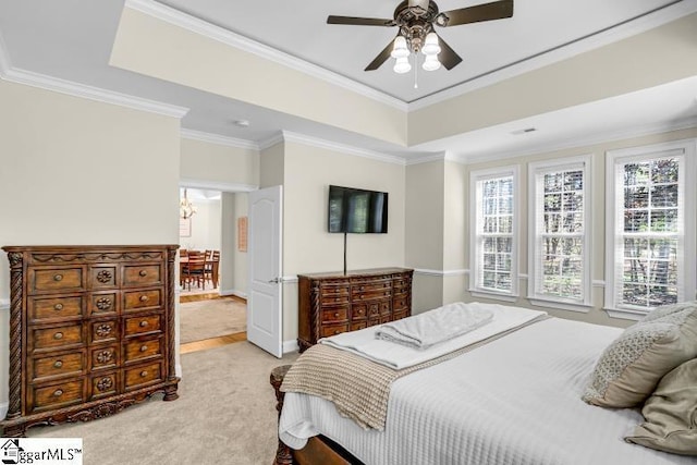 bedroom featuring a tray ceiling, multiple windows, and crown molding