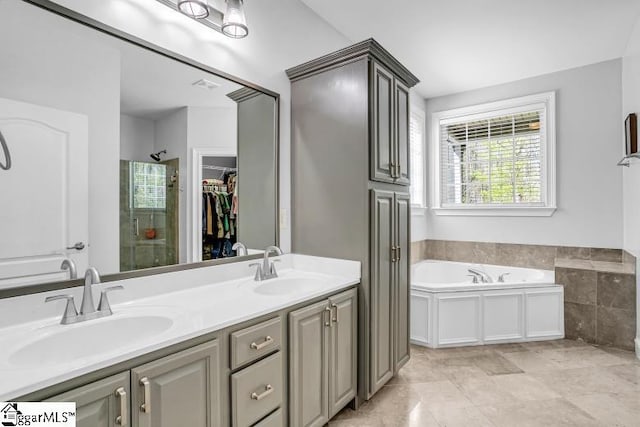 full bath featuring a sink, a walk in closet, a shower stall, and a garden tub