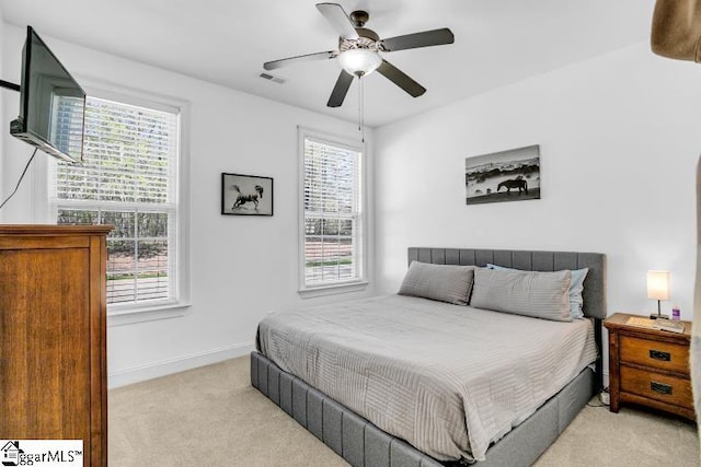 bedroom featuring baseboards, visible vents, multiple windows, and light colored carpet