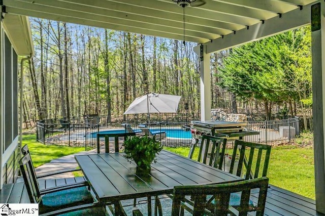 view of patio featuring a fenced in pool, outdoor dining area, a wooden deck, and fence