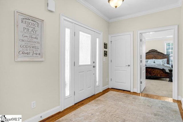 foyer with crown molding, wood finished floors, and baseboards