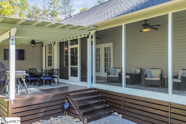 deck featuring a sunroom, ceiling fan, and outdoor dining area
