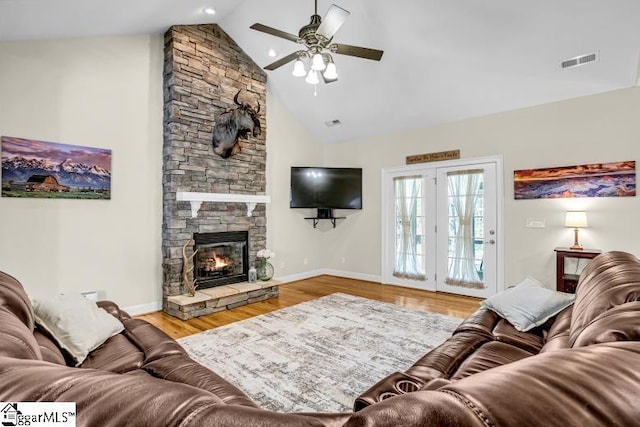 living room with high vaulted ceiling, a fireplace, a ceiling fan, visible vents, and wood finished floors