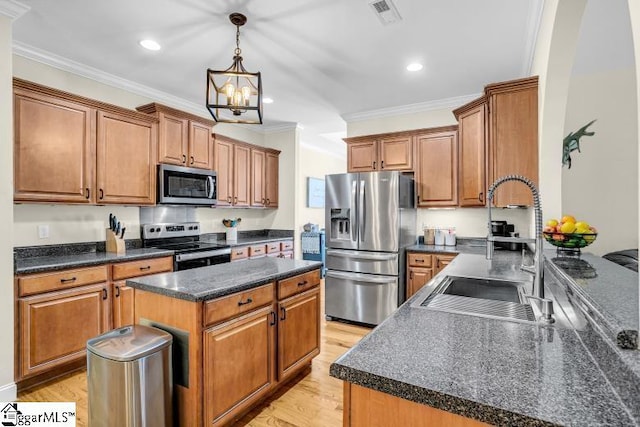 kitchen with a notable chandelier, a sink, appliances with stainless steel finishes, dark countertops, and crown molding