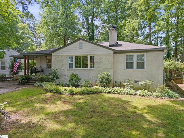 view of front facade with brick siding, a front yard, a porch, and a chimney
