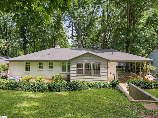 rear view of property featuring a chimney, a yard, fence, and brick siding