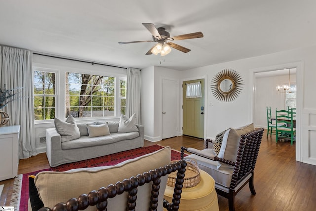 living area with ceiling fan with notable chandelier and hardwood / wood-style floors