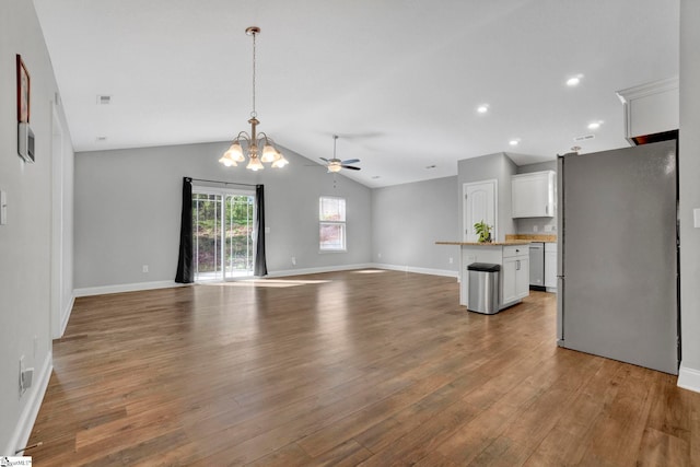 unfurnished living room featuring ceiling fan with notable chandelier, recessed lighting, wood finished floors, lofted ceiling, and baseboards