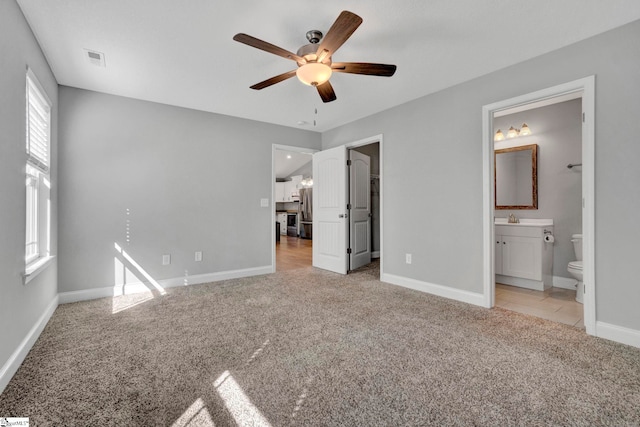 unfurnished bedroom featuring baseboards, stainless steel refrigerator with ice dispenser, visible vents, light colored carpet, and a sink