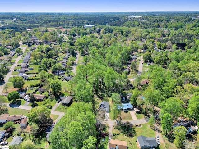 drone / aerial view featuring a wooded view and a residential view
