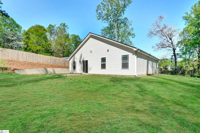 back of house featuring a fenced backyard and a lawn