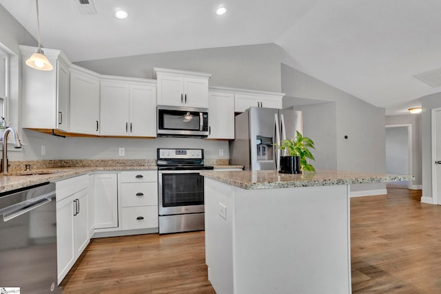 kitchen featuring a center island, a sink, appliances with stainless steel finishes, light wood finished floors, and vaulted ceiling