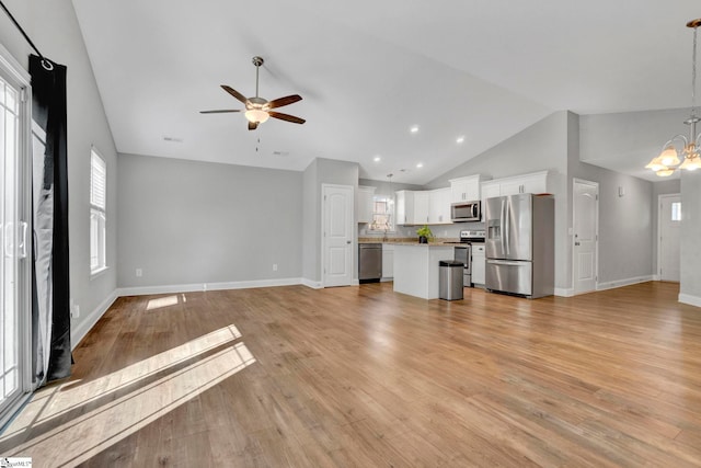 unfurnished living room featuring baseboards, light wood-style floors, ceiling fan with notable chandelier, and vaulted ceiling