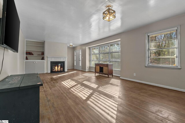 1020 Woodburn Rd, Spartanburg, SC 29302 - unfurnished living room with a glass covered fireplace, built in shelves, baseboards, and wood finished floors