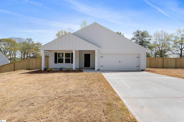 view of front of property featuring driveway, a garage, a front yard, and fence