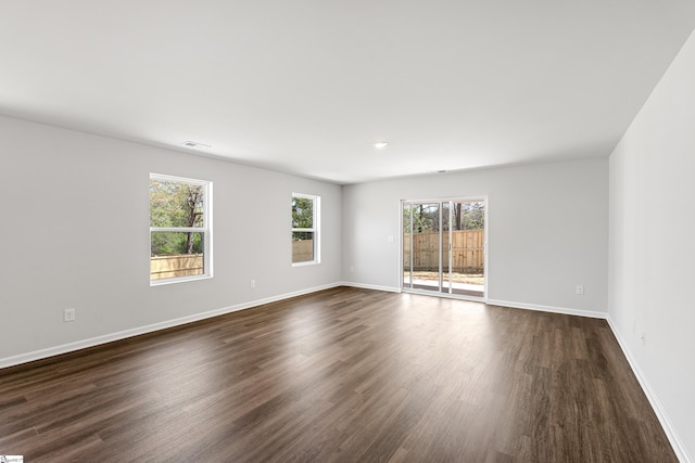 spare room with visible vents, baseboards, and dark wood finished floors