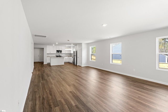 unfurnished living room with recessed lighting, visible vents, dark wood-style flooring, and baseboards