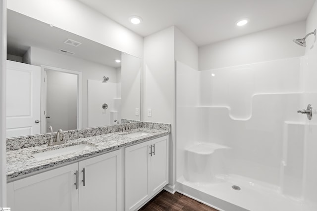 bathroom with a sink, visible vents, a shower stall, and wood finished floors