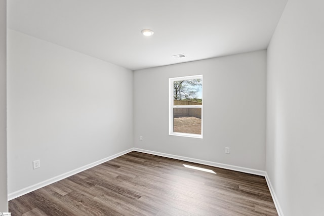 spare room featuring visible vents, baseboards, and wood finished floors