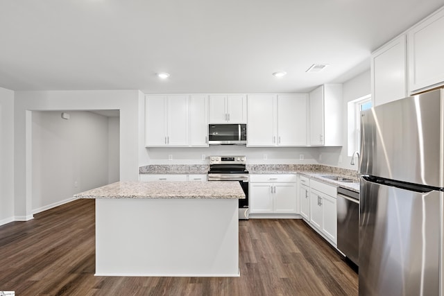 kitchen featuring visible vents, a sink, stainless steel appliances, dark wood-type flooring, and a kitchen island