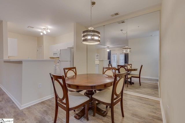 dining space with visible vents, baseboards, and light wood-style floors