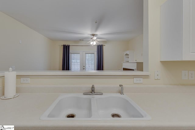 room details with a sink, light countertops, ceiling fan, and white cabinetry