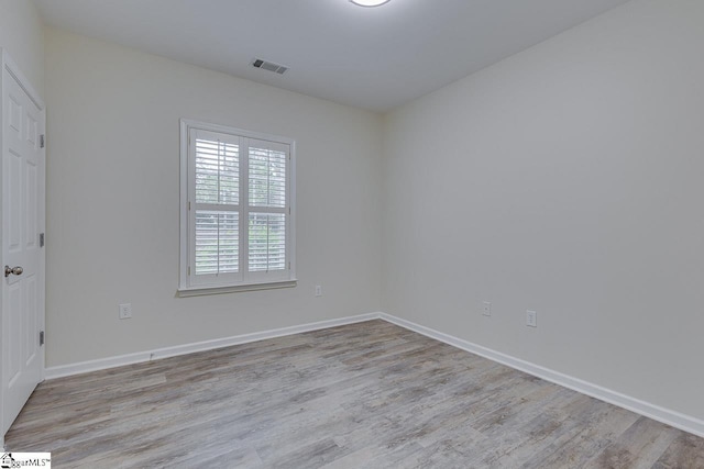 unfurnished room with wood finished floors, baseboards, and visible vents