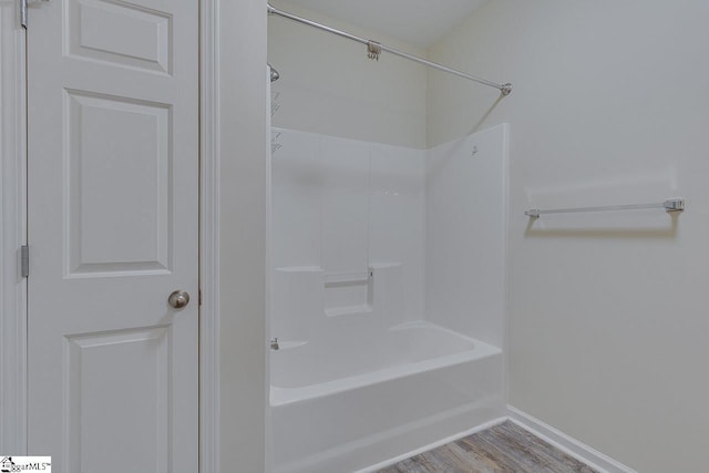 full bathroom with wood finished floors, shower / tub combination, and baseboards