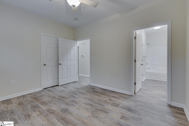 unfurnished bedroom with wood finished floors, ceiling fan, baseboards, and connected bathroom