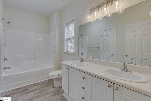 bathroom featuring washtub / shower combination, a sink, toilet, and wood finished floors