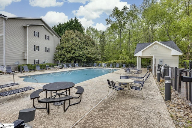 pool with a patio area, fence, and an outdoor structure