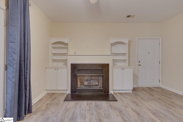 unfurnished living room featuring light wood-style floors, built in features, and baseboards