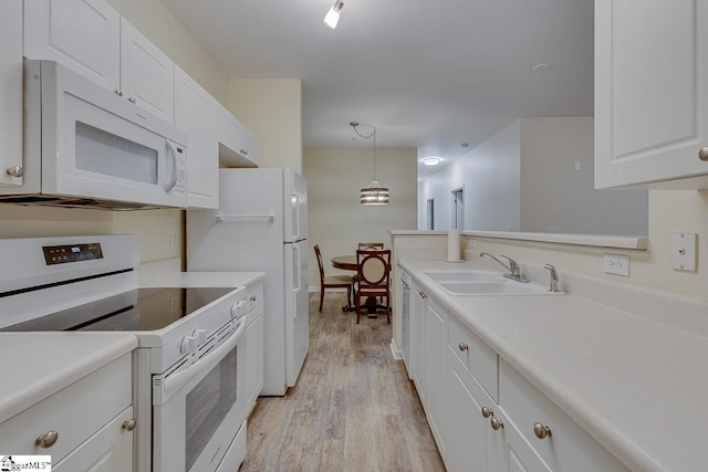 kitchen with light wood-type flooring, white appliances, light countertops, white cabinets, and a sink