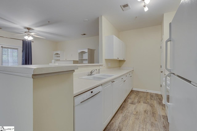 kitchen featuring white appliances, light countertops, light wood-style floors, visible vents, and a sink