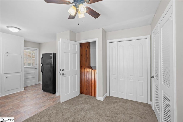 unfurnished bedroom featuring a closet, freestanding refrigerator, baseboards, and a ceiling fan