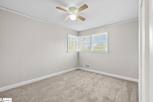 carpeted empty room with visible vents, baseboards, crown molding, and ceiling fan