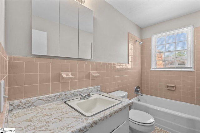 bathroom featuring toilet, vanity, shower / washtub combination, and tile walls