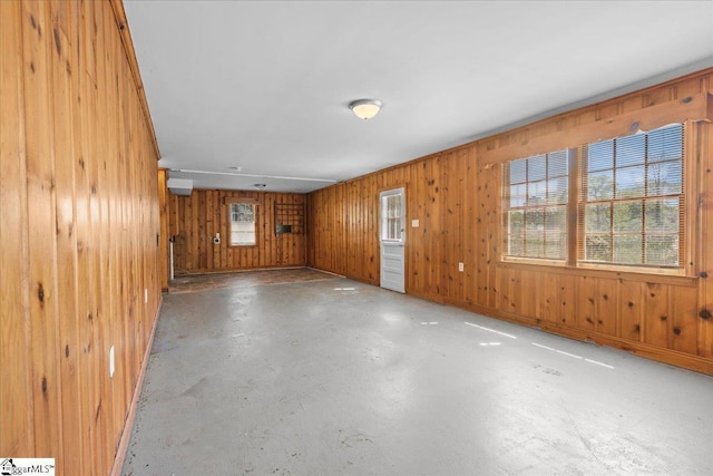 empty room with wood walls and concrete flooring