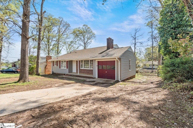 view of front of property with concrete driveway, an attached garage, and a chimney