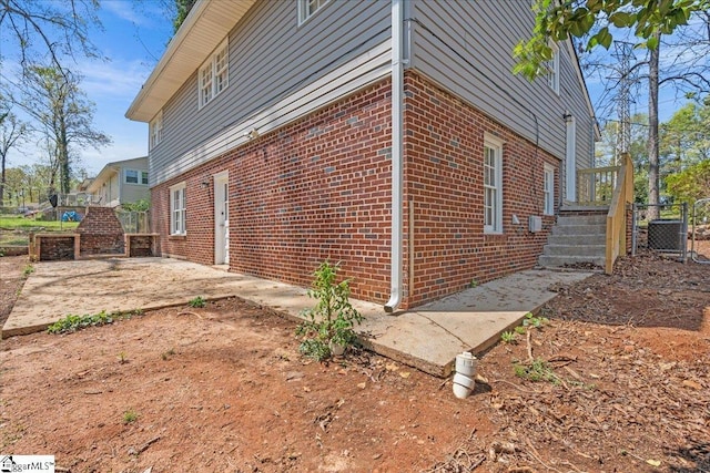 view of side of home with brick siding, fence, and a patio area