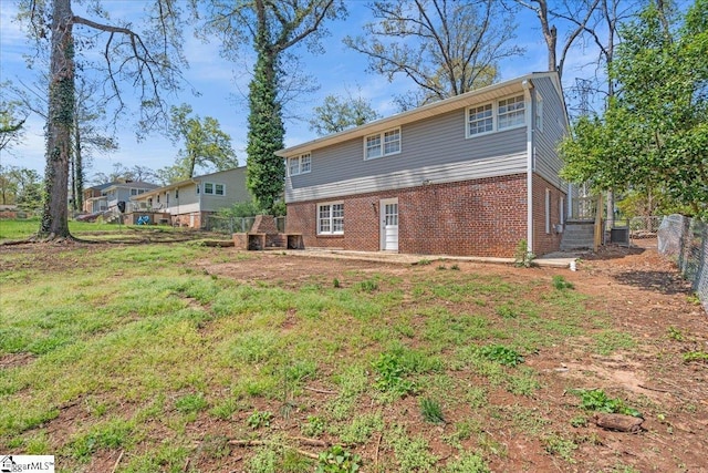 rear view of property featuring brick siding, fence, and central air condition unit