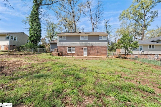 rear view of house with brick siding, fence, and a lawn