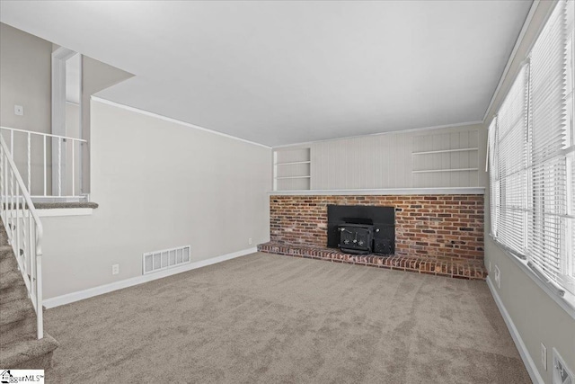 unfurnished living room with visible vents, a wealth of natural light, carpet flooring, and stairs