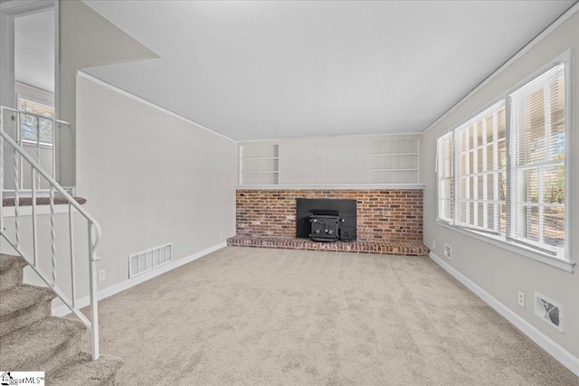 unfurnished living room featuring a wood stove, visible vents, and plenty of natural light
