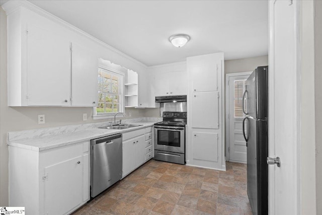 kitchen featuring white cabinets, a sink, appliances with stainless steel finishes, under cabinet range hood, and stone finish flooring
