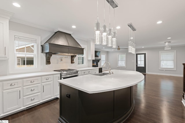 kitchen featuring custom exhaust hood, a sink, light countertops, stainless steel stove, and recessed lighting