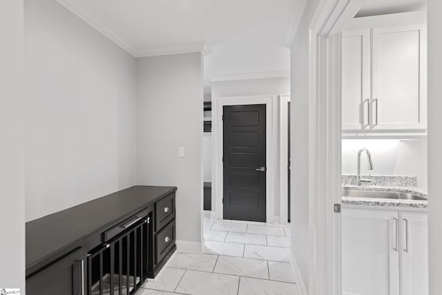 interior space with baseboards, marble finish floor, a sink, and crown molding