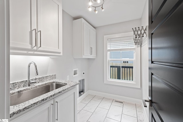 kitchen with baseboards, white cabinetry, visible vents, marble finish floor, and a sink