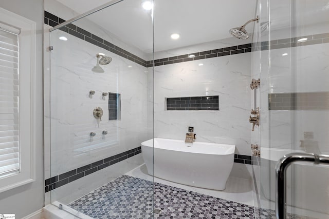 bathroom featuring a shower stall, a freestanding tub, and tile walls